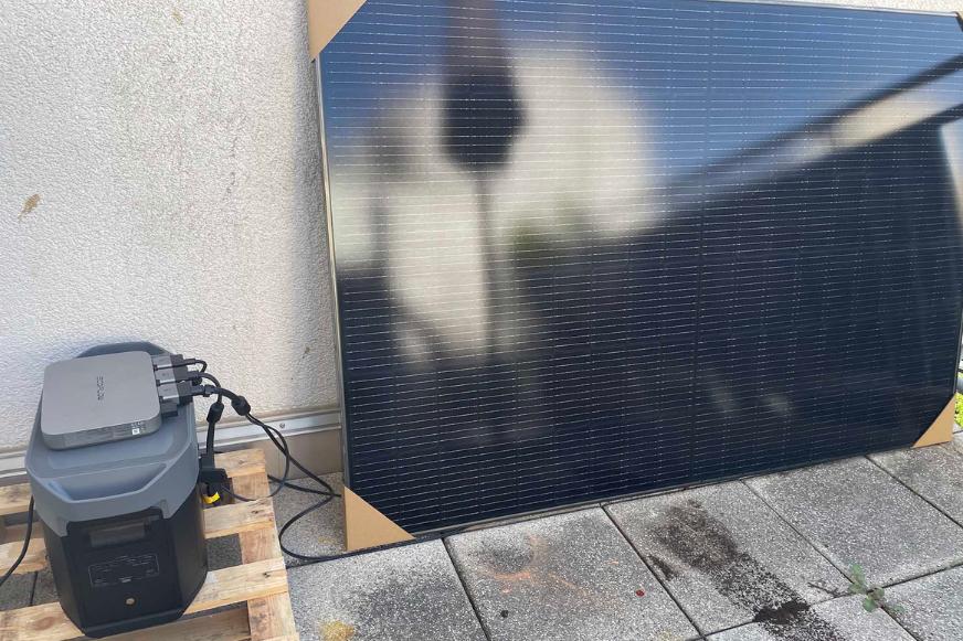 Das EcoFlow PowerStream Balkonrkaftwerk Komplettset, steht auf der Terrasse, der Delta 2 Max Speicher ist mit dem Mikrowechselrichter verkabelt und das Solarmodul steht daneben an die Wand gelehnt.
